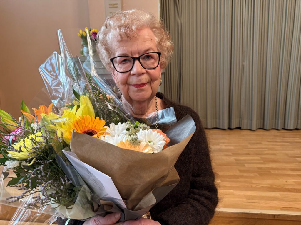 Marja-Leena Mikkola onnittelukukkien kanssa palkintojen jakotilaisuudessa 9.4.2026.